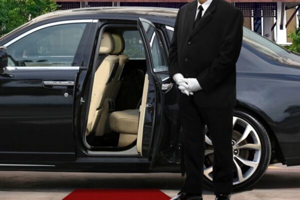 Limo driver standing next to opened car door with red carpet Limo driver standing next to opened car door with red carpet